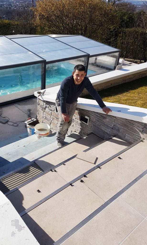 Le carreleur pour la Canonne durant la pose du carrelage autour d'une piscine à Triel-Sur-Seine (Yvelines, 78)